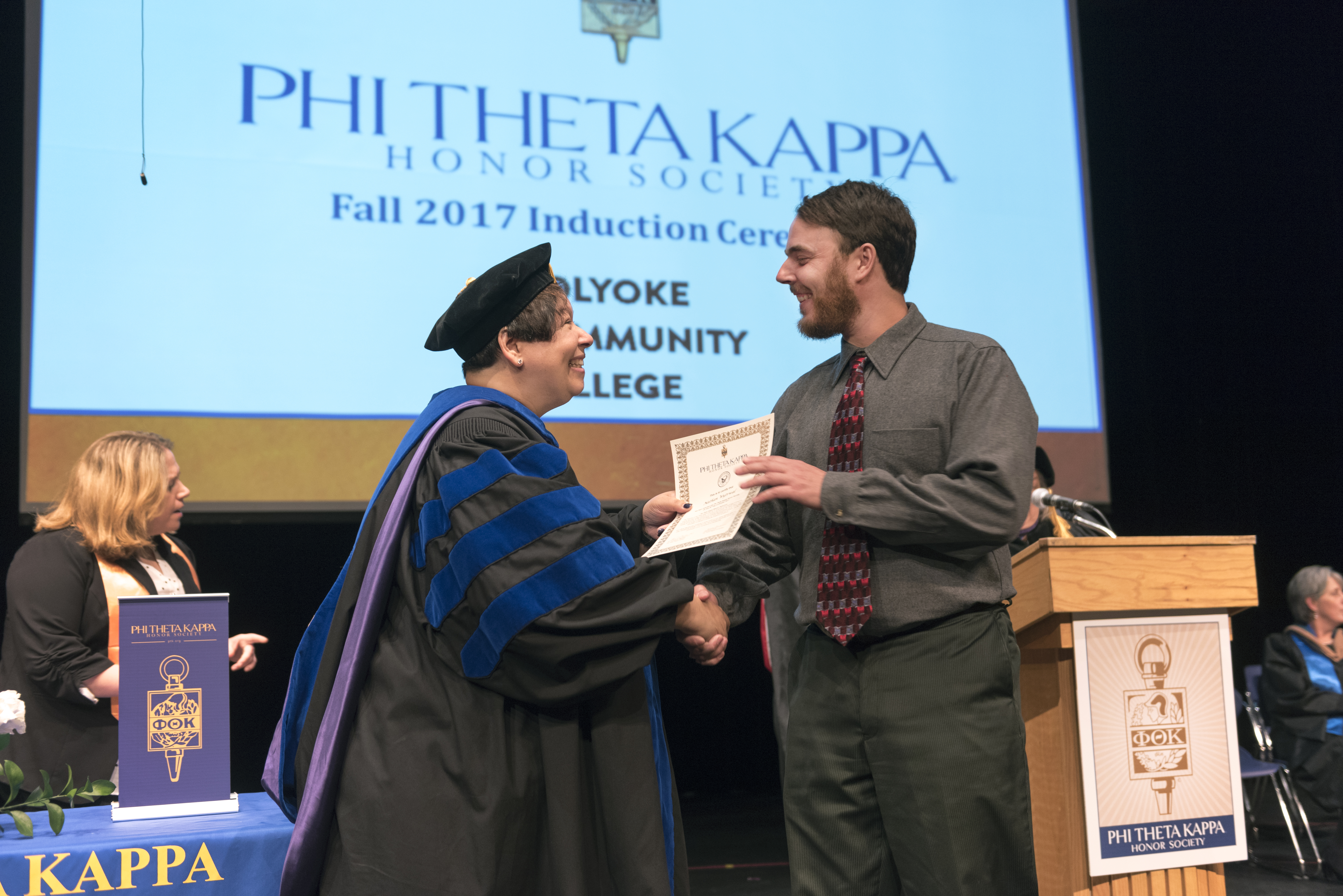 Christina Royal hands a certificate to a student at PTK graduation